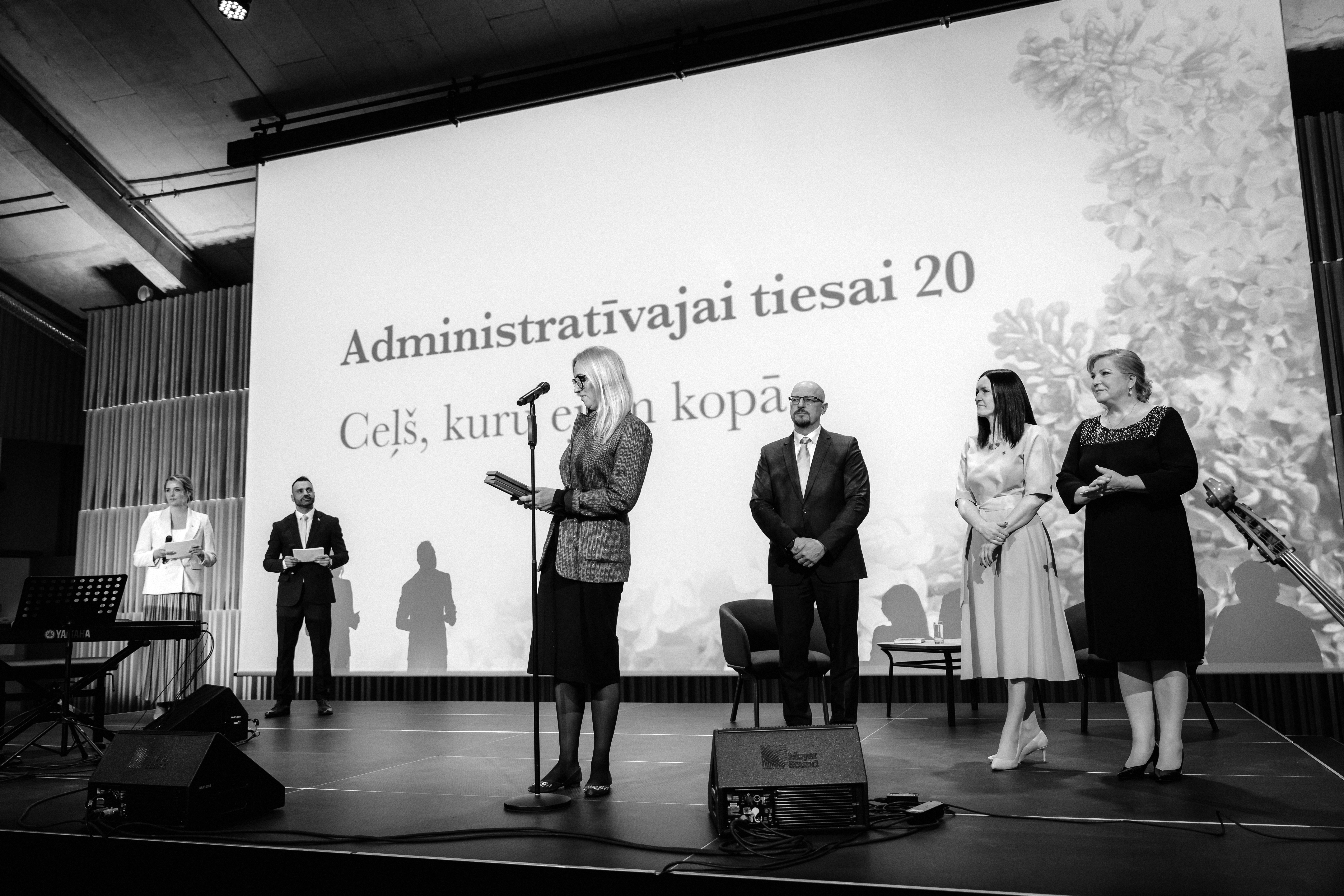 Tieslietu ministrijas parlamentārā sekretāre Lauma Paegļkalna nodod ministres pateicību trīs administratīvo tiesu priekšsēdētājiem – Administratīvās apgabaltiesas priekšsēdētājam Ojāram Priedītim, Administratīvās rajona tiesas priekšsēdētājai Aigai Putniņai un Senāta Administratīvo lietu departamenta priekšsēdētājai Veronikai Krūmiņai